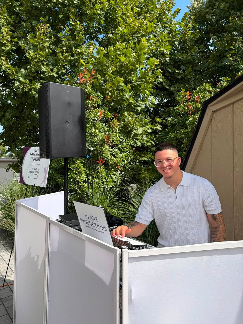 DJ Ant smiling behind the decks at an outdoor event